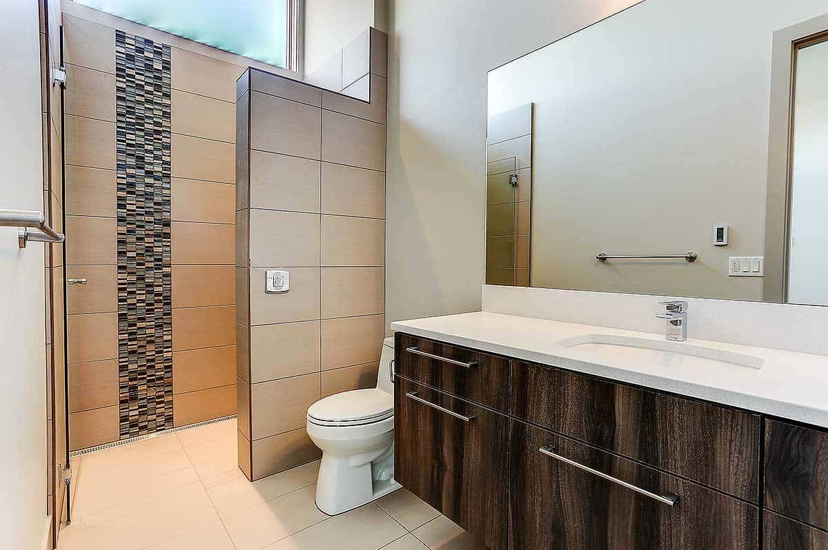 这间浴室设有一个漂浮的梳妆台、一个厕所和一个带有线性马赛克瓷砖的步入式淋浴间。