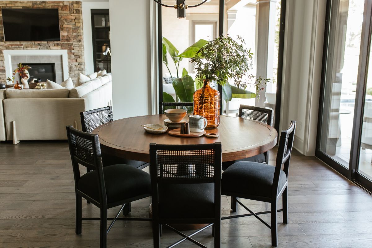 室内用餐室配有六座圆形木制餐桌和落地玻璃墙壁。