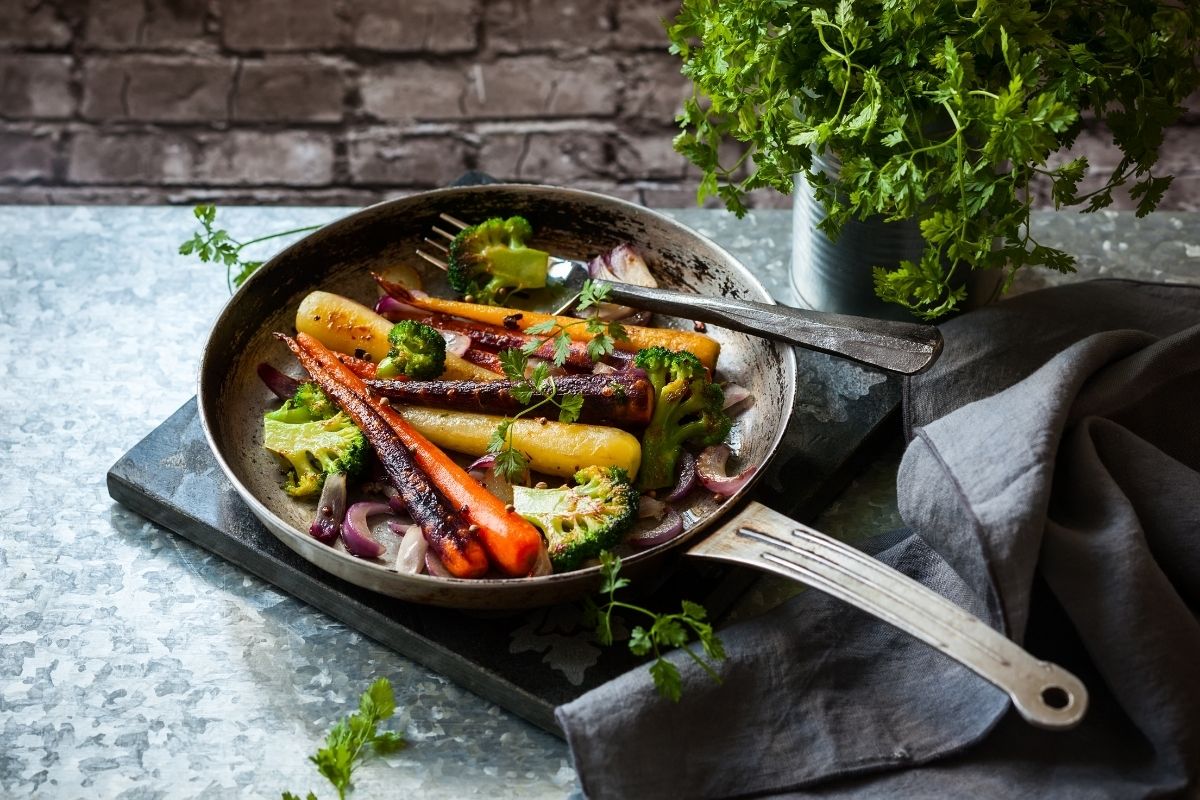 一个健康的西兰花与烤彩虹胡萝卜在铸铁锅。
