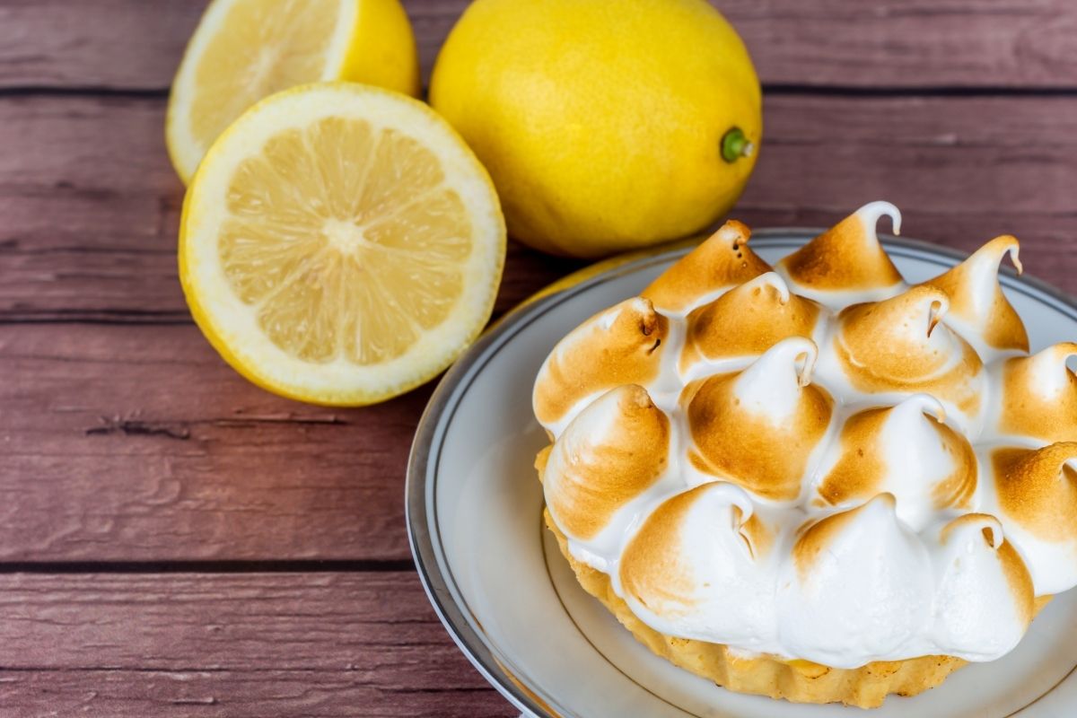 木桌上的新鲜自制柠檬派和蛋白酥皮和柠檬柑橘类水果。