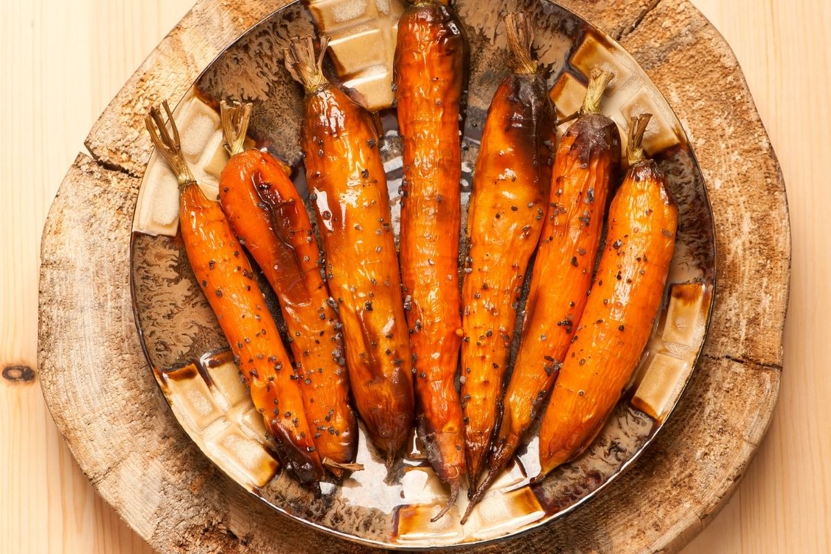 甜美独特的烤肉桂胡萝卜，装在棕色盘子里。