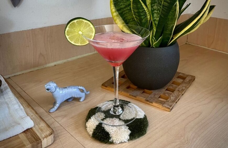 粉红色的伏特加酒，上面装饰着石灰，送给鸡尾酒玻璃杯