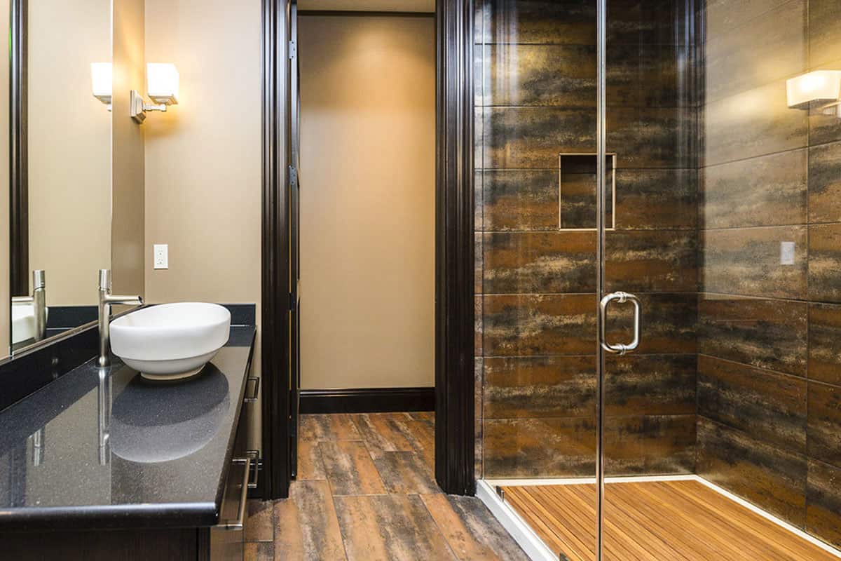 主浴室里有一个水槽梳妆台和一间步入式淋浴间，淋浴间由一扇玻璃铰链门围合。