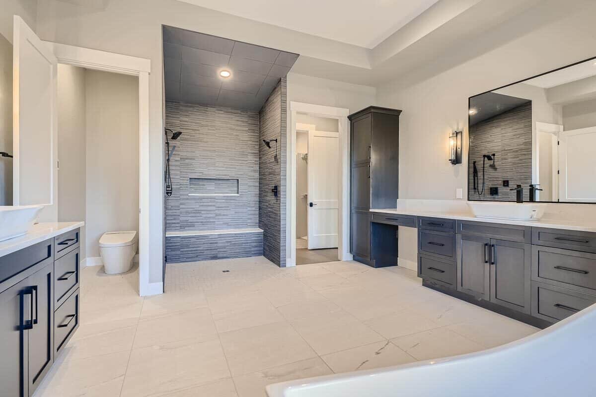 主浴室设有一间卫生间和一间步入式淋浴间，配有一条铺着瓷砖的长凳和两个淋浴头。