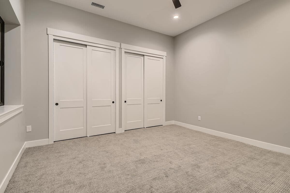 另一间卧室铺着地毯，衣柜嵌在白色滑动门里。