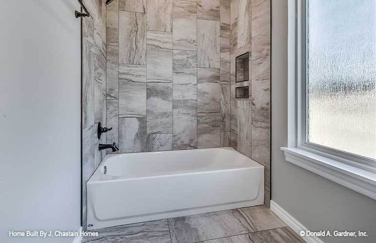 另一间浴室有大理石瓷砖墙，配有浴缸和淋浴组合。