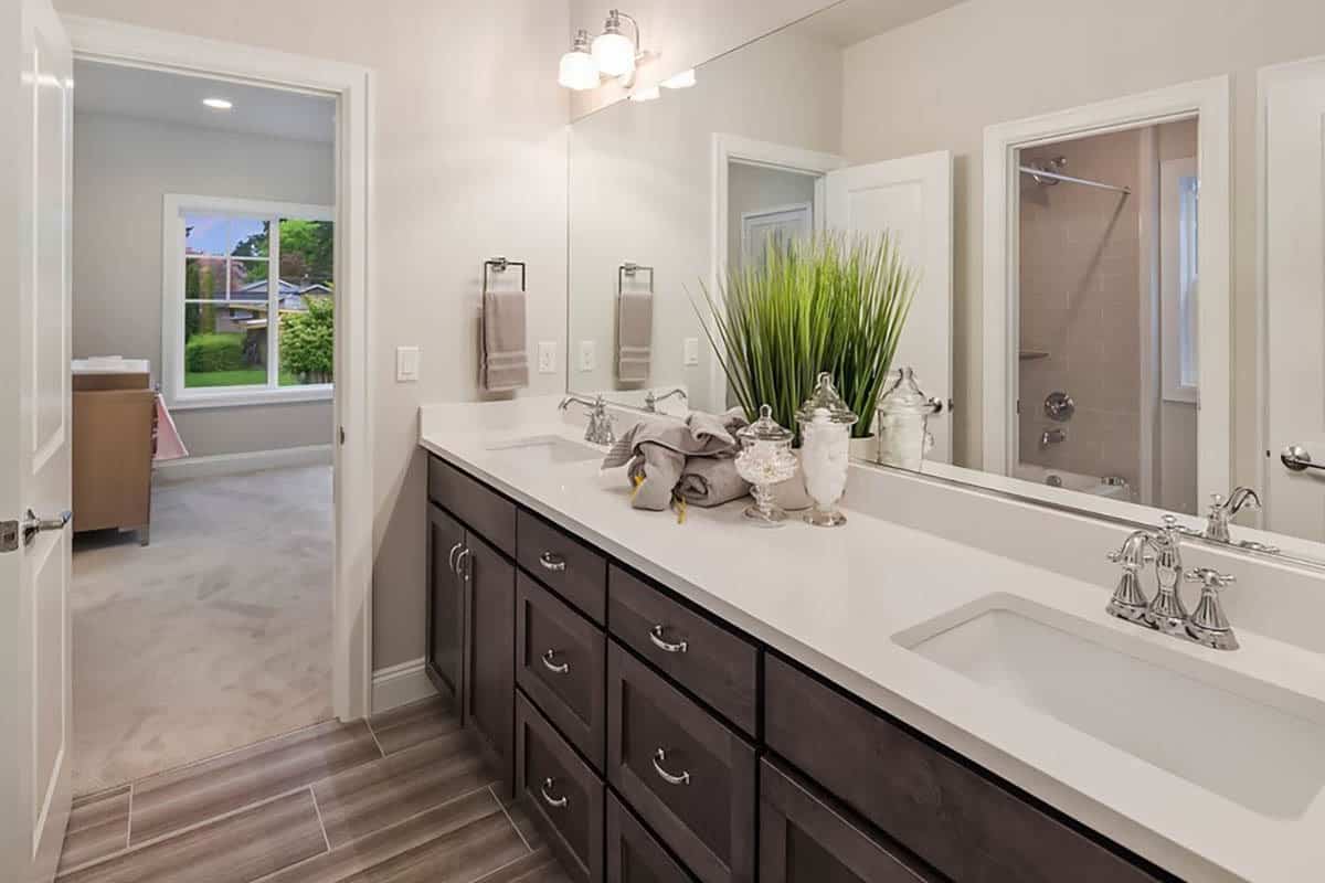 这间浴室设有一个双洗手池梳妆台，浴缸和淋浴组合在矩形镜子中反射。