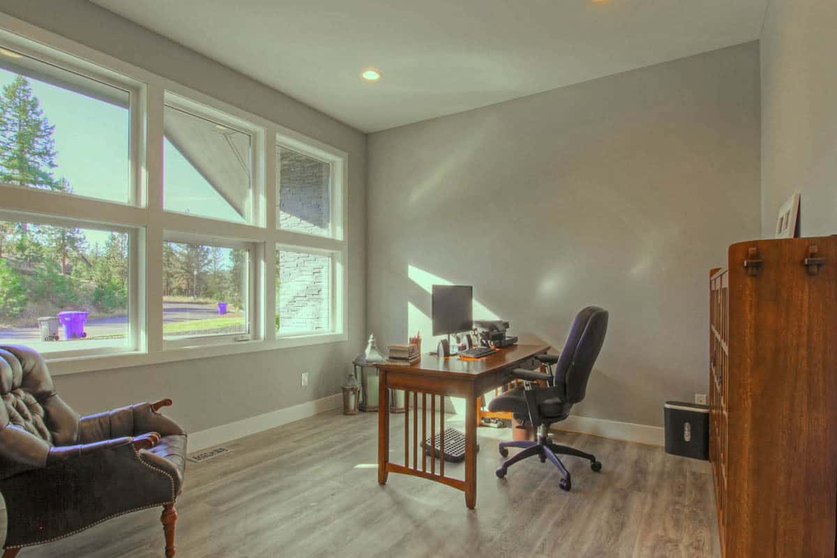 家庭办公室，有一张木桌，真皮座椅，还有很多可以俯瞰前院的窗户。