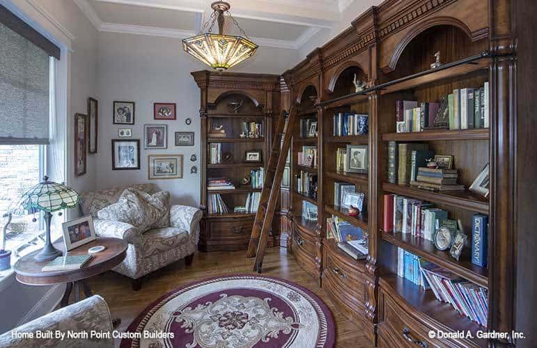 书房里有一个嵌壁式书柜，有图案的扶手椅，硬木地板上铺着圆形地毯。