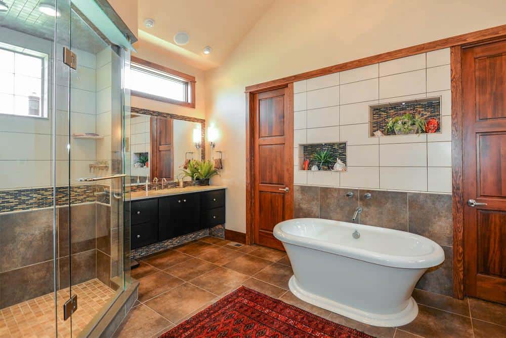 主浴室配有深色木制梳妆台，步入式淋浴间和独立浴缸配有红色地毯。