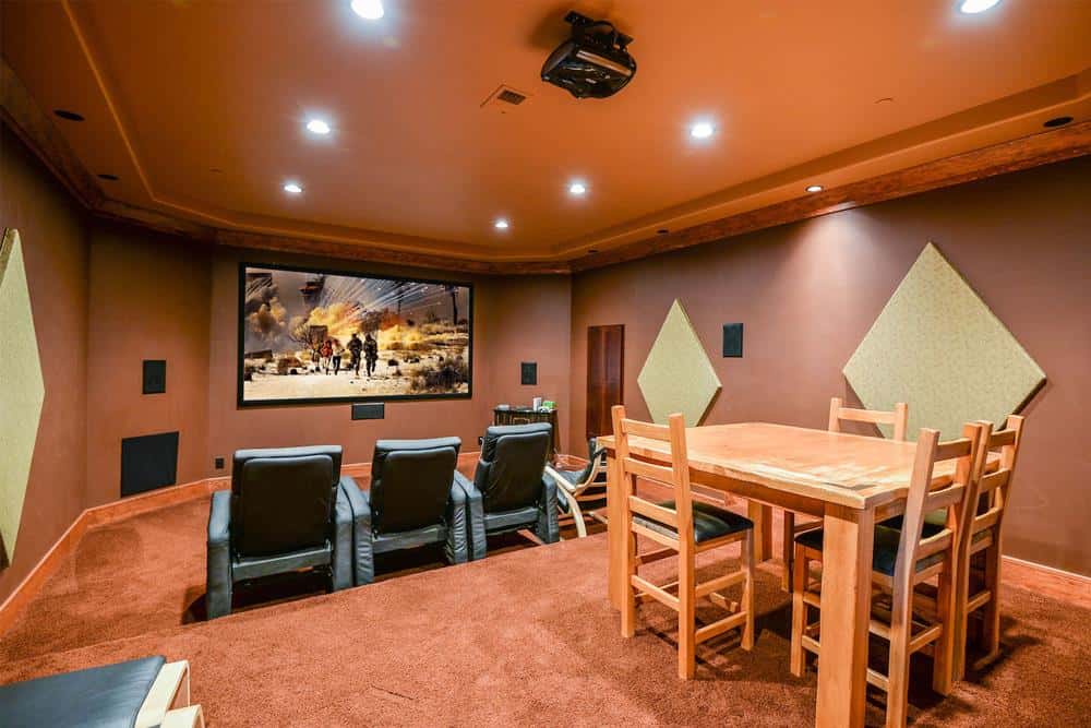 家庭影院有一个木制餐饮，舒适的躺椅和一个大屏幕。