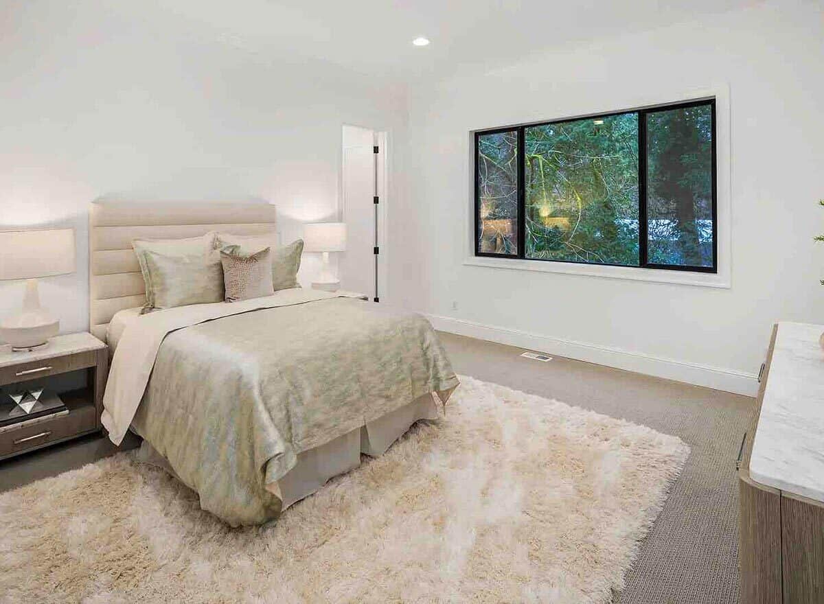 这间卧室里有一些浅色的木柜和一张米色的软垫床，上面铺着一张粗糙的地毯。
