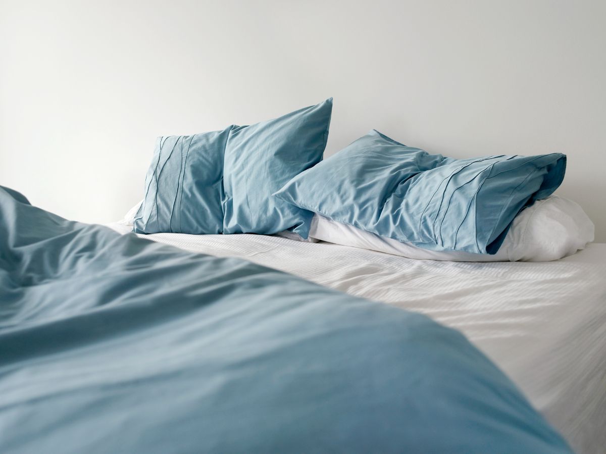 蓝色的枕套和被套，白色的床单在白色的墙壁上