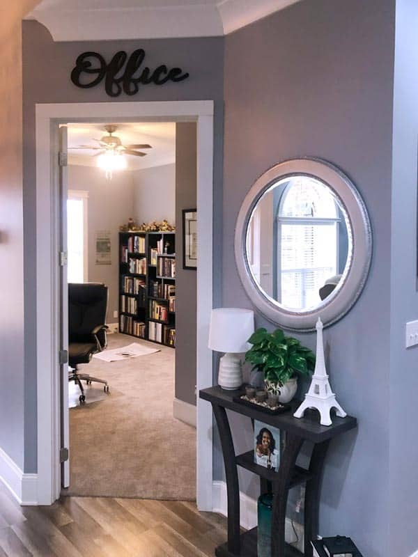 家庭办公室的入口处装饰着一面圆镜子和一张小桌子。