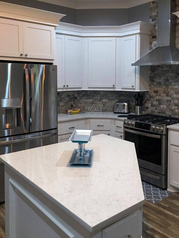 厨房配有不锈钢电器、白色橱柜和一个带大理石台面的中央岛台。