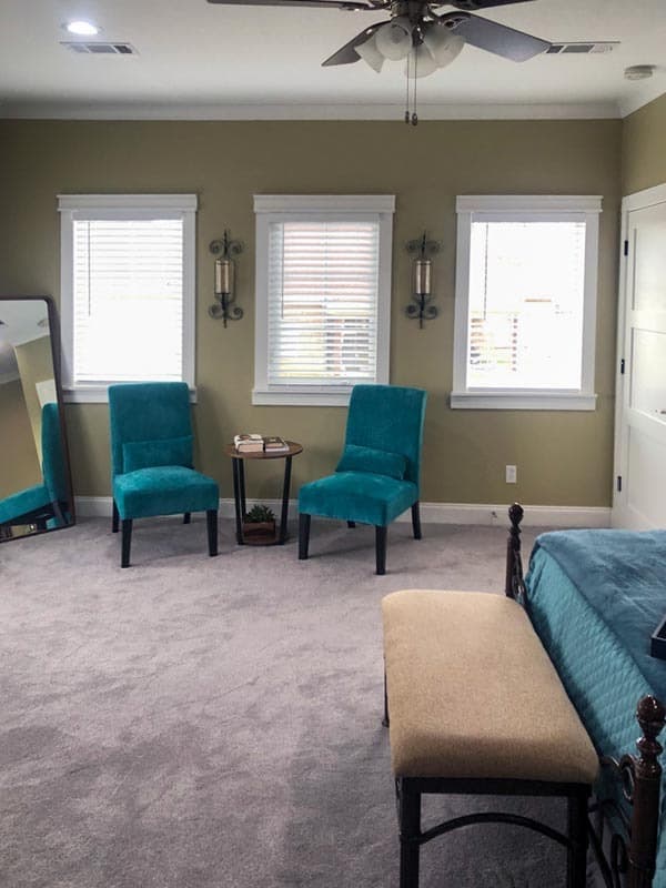 蓝绿色的天鹅绒椅子和床为这个中性的卧室增添了色彩。