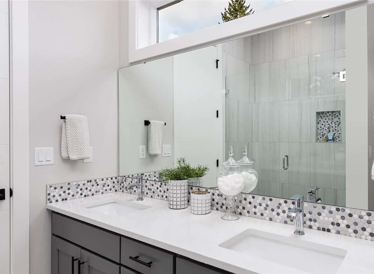 浴室有一个双洗手台梳妆台，上面有一面矩形无框镜子。