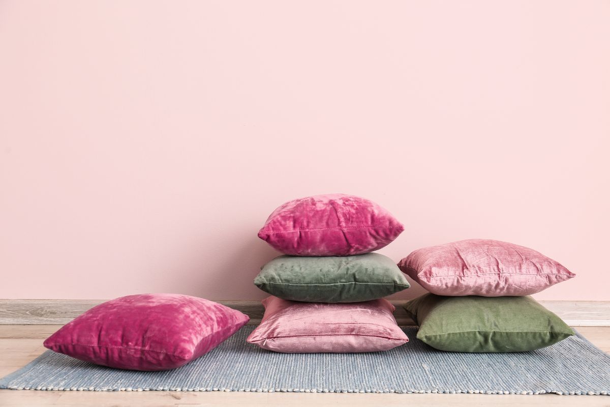 粉色和绿色的抱枕在地板上，粉红色的背景