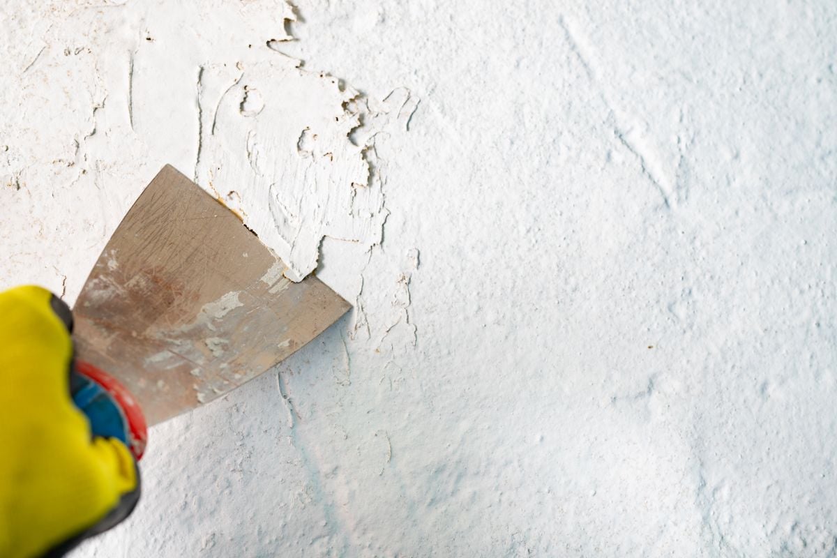 一个人用刀擦掉损坏的油漆。