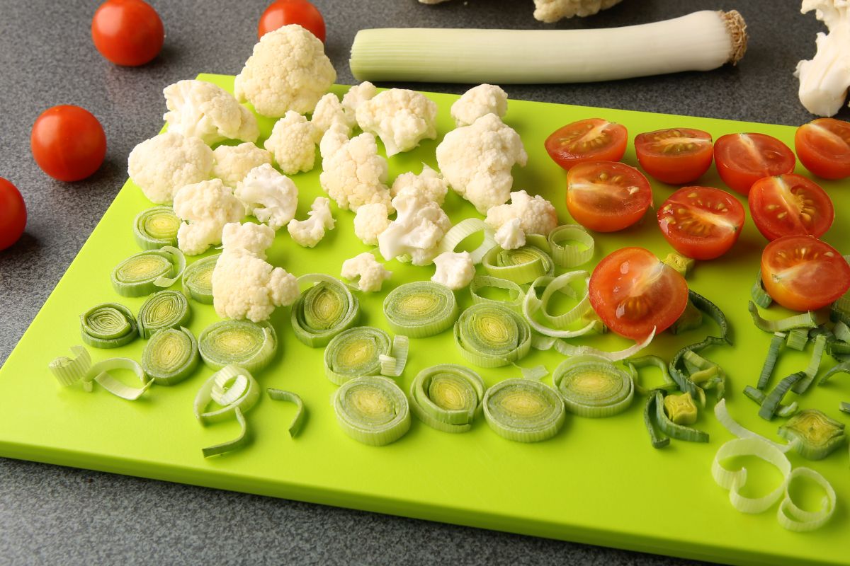 切片蔬菜和绿色塑料砧板。