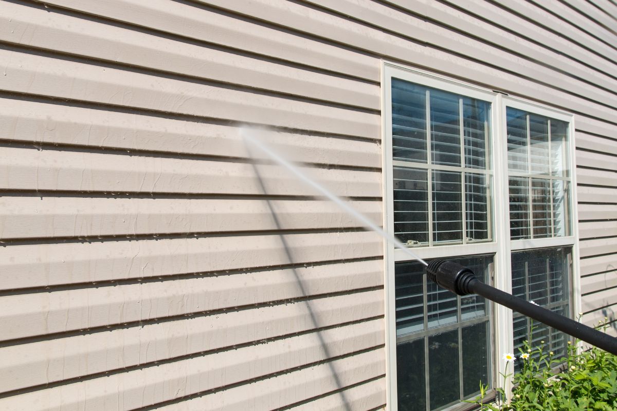 带窗户的米色房屋的强力清洗壁板