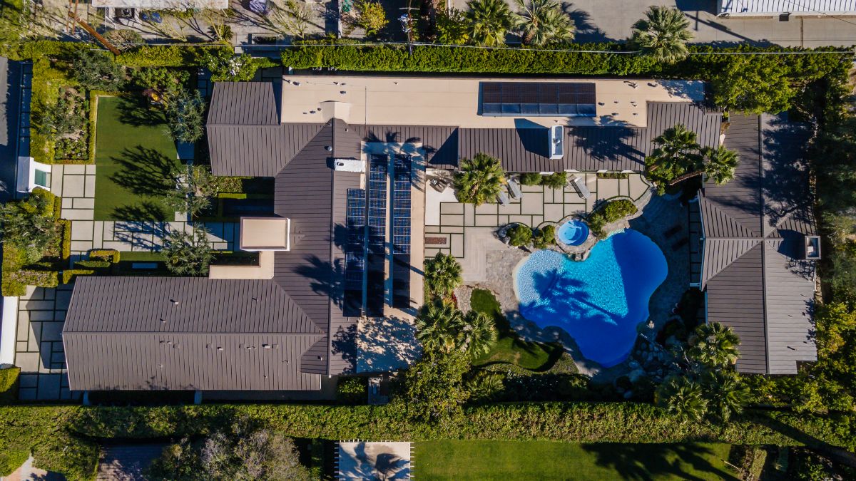 房子的鸟瞰图，突出了蓝绿色的游泳池和周围的自然环境。图片来自Toptenrealestatedeals.com