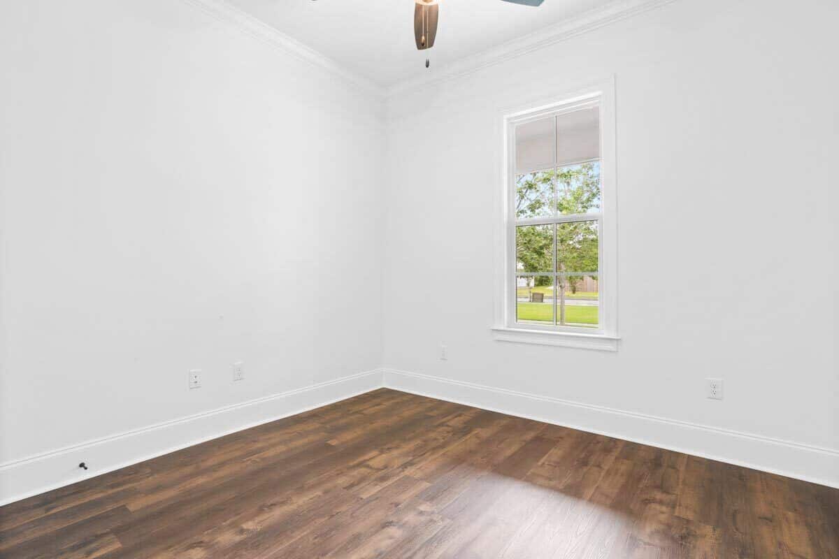 这个卧室里有硬木地板,白墙,一个框架窗口允许自然光线。