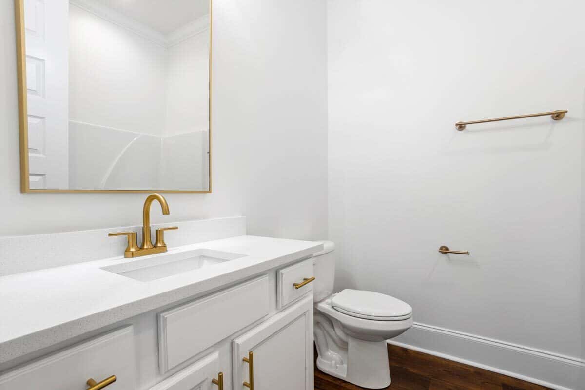 这浴室配备了一个卫生间,水槽的虚荣心,浴缸和淋浴组合反映在黄铜框架镜子。