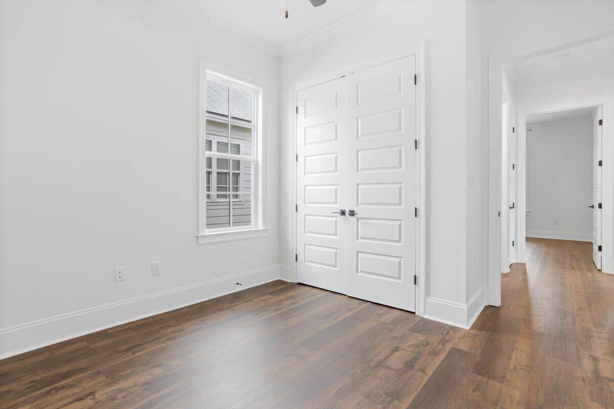 另一个卧室里有硬木地板和一个大壁橱隐藏在白色的双扇门后面。