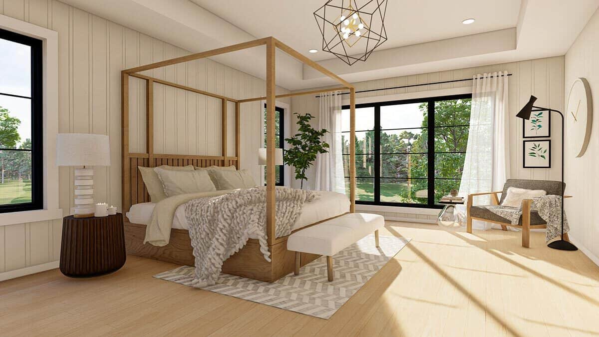 主卧室有一把软垫扶手椅和一张天篷床，床尾有一张白色长凳。