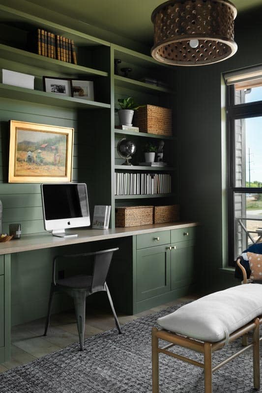 家庭办公室有一个内置的桌子和书架，与绿色的墙壁融为一体。