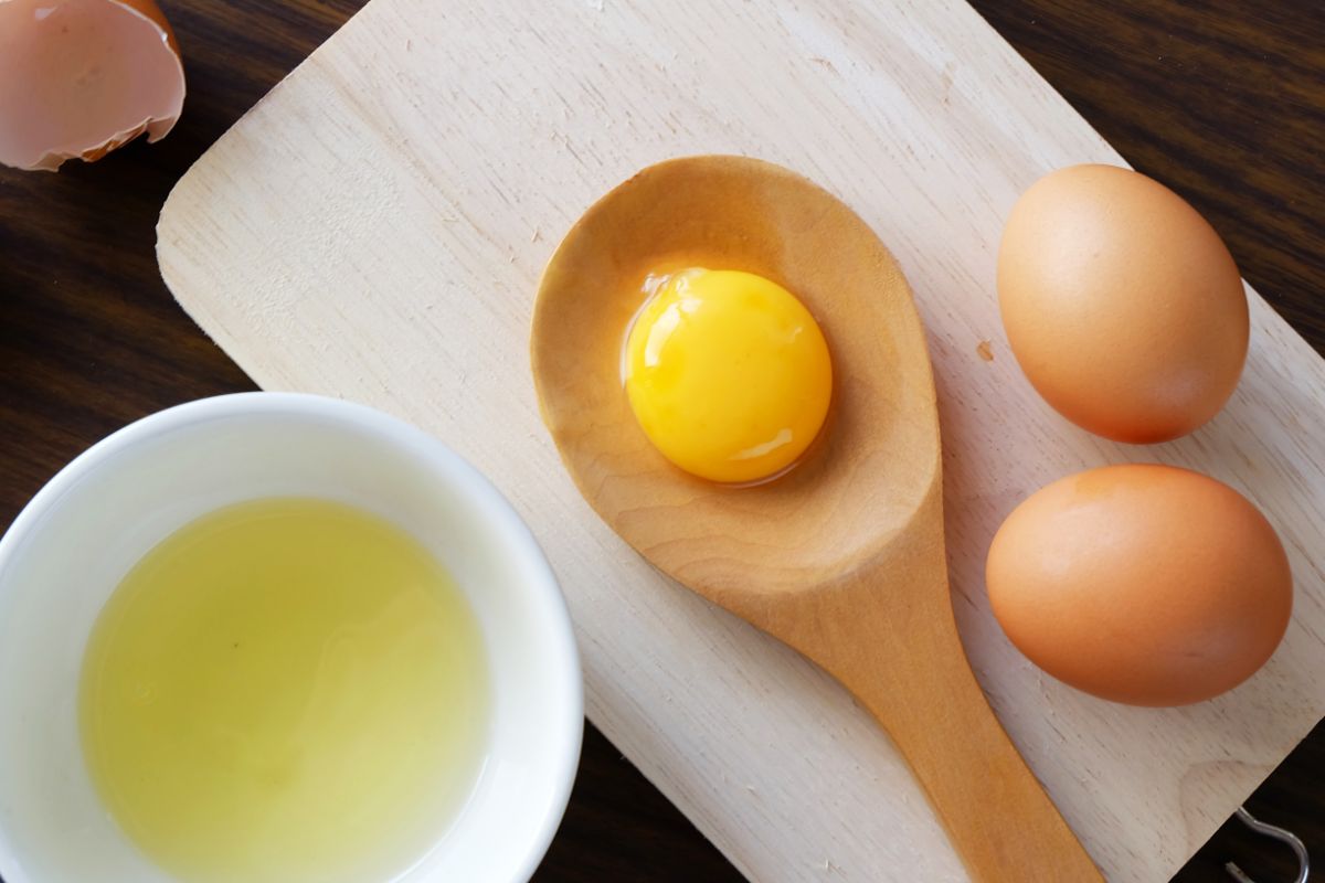 新鲜鸡蛋放在勺子和砧板上。