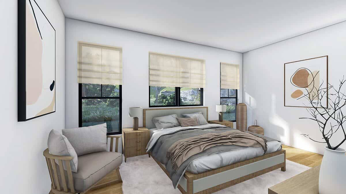主卧室有一个舒适的木床，一个软垫扶手椅，和抽象的艺术品装饰原始的白色墙壁。