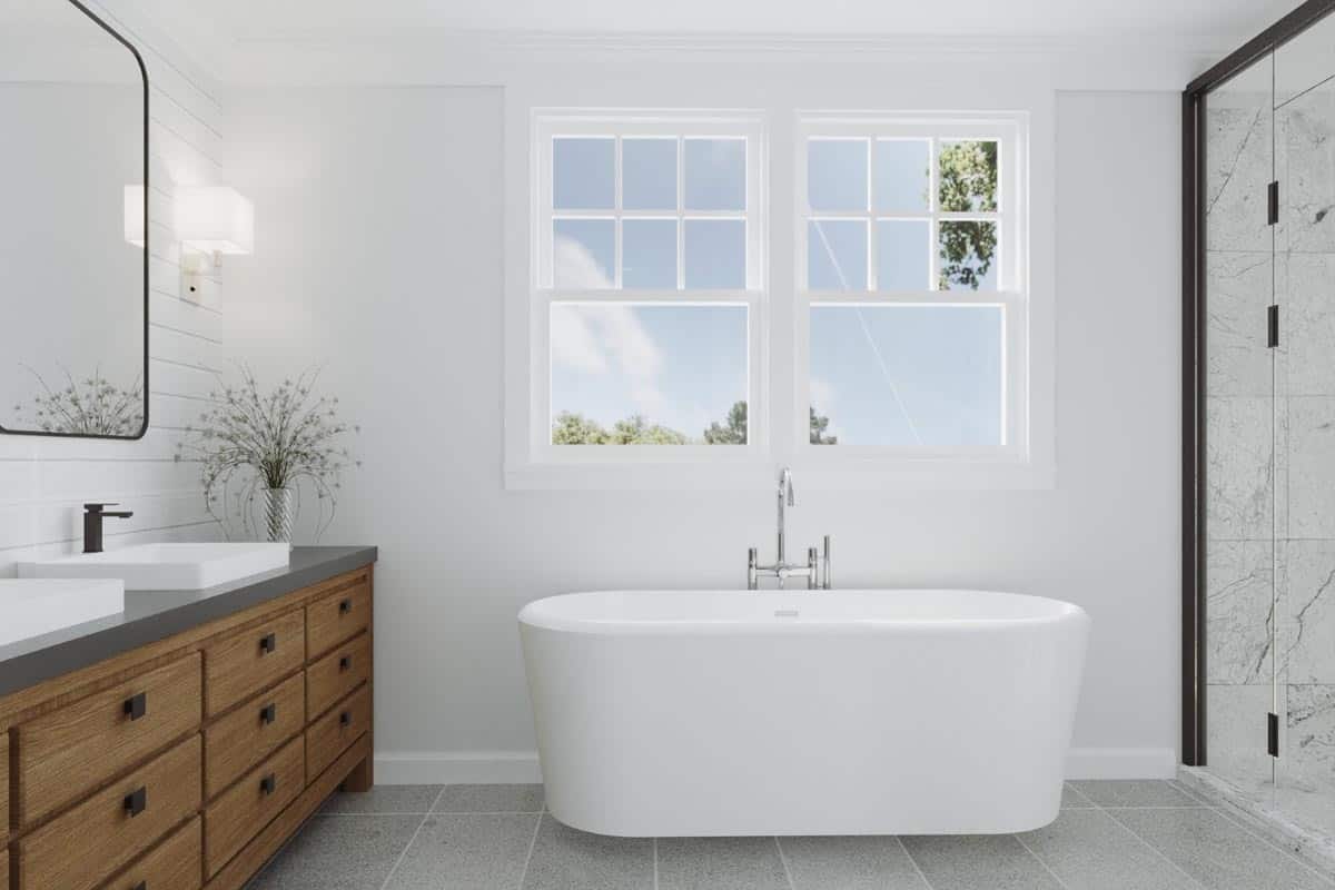 主浴室带有双洗手池梳妆台和一个独立的浴缸，放置在白色框窗下。
