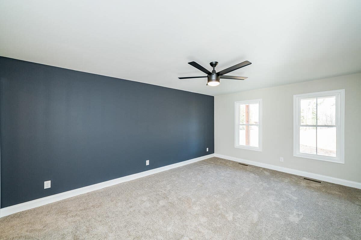 主卧室的地毯的地板上,深蓝口音墙和吊扇。