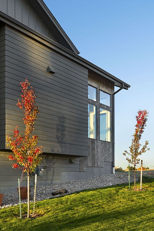侧视图的房子坐落在一个倾斜的地段。木质外墙与郁郁葱葱的草坪相得益彰。