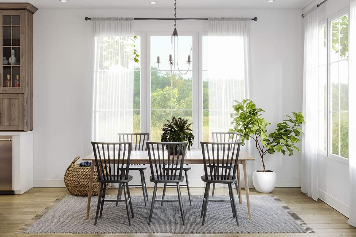 用餐区有一种新鲜的盆栽植物和窗帘装饰的大窗户，光线和空气的氛围。
