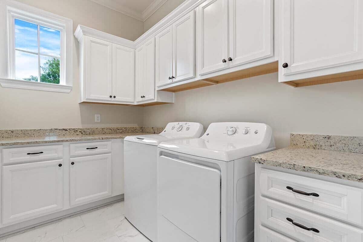 洗衣房配有白色洗衣机和烘干机，花岗岩台面和充足的存储空间。