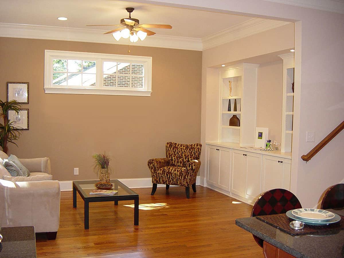 家庭娱乐室配有白色内置家具和织物软垫椅子，配以玻璃面咖啡桌。