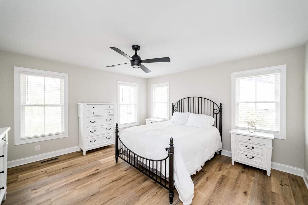 主卧室里有白色橱柜和一张铺着硬木地板的华丽金属床。