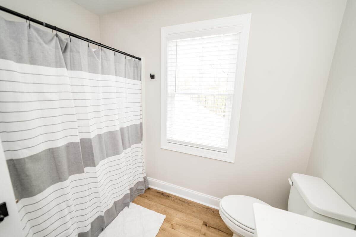 浴室里有一个浴缸和淋浴组合，用灰色条纹窗帘包裹着。