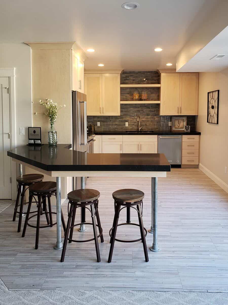 厨房配有白色橱柜、瓷砖后挡板、浮动架子和倾斜的吧台。