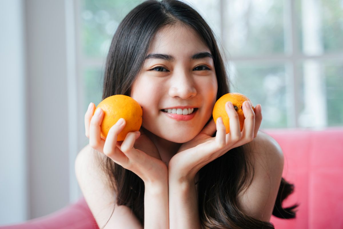 一个皮肤白皙的女人拿着橘子。