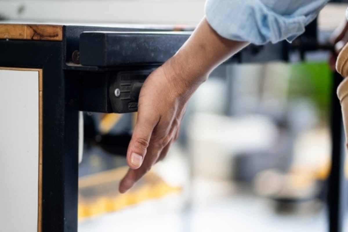 一个工人的手按在工作台锯的安全电源开关上。