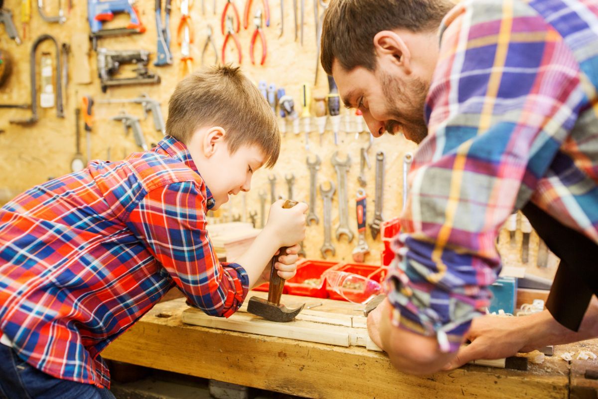 一个男人教他的孩子如何把钉子从木头里取出来。