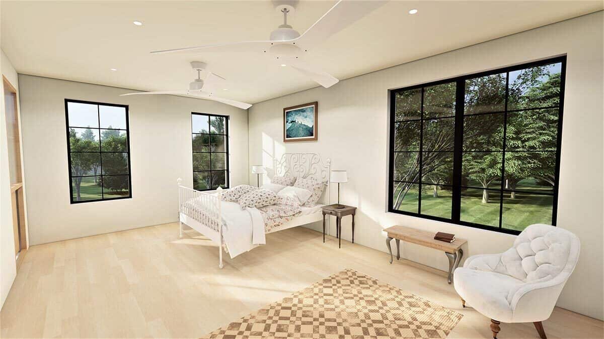 主卧有一张华丽的白色床，一把舒适的簇绒椅子，硬木地板上铺着一张有图案的地毯。