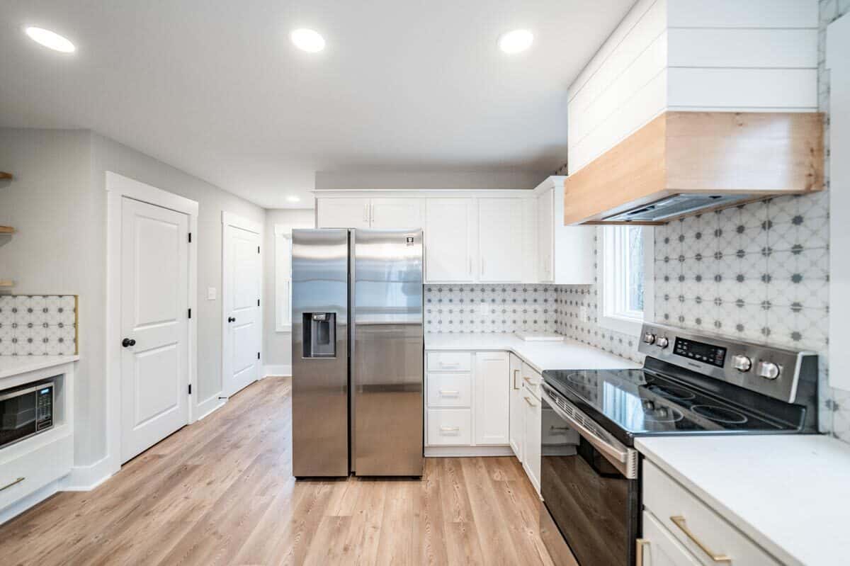 厨房配有不锈钢电器、白色的橱柜,石英台面。