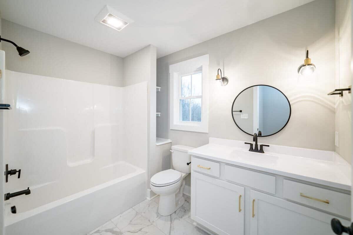 浴室用白色虚荣,厕所在窗下,内置的架子,和一个浴缸和淋浴组合。