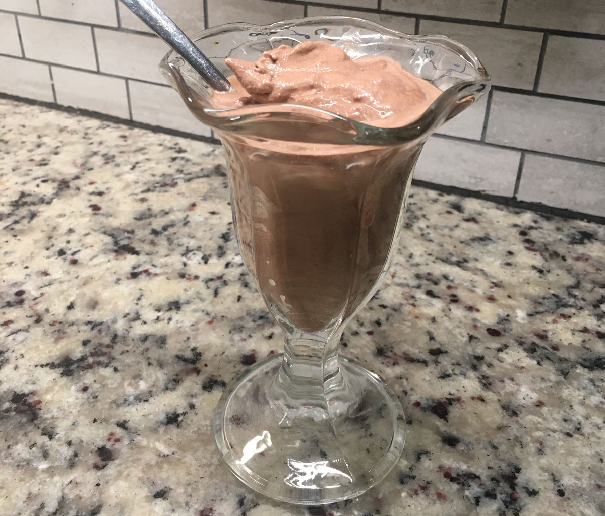 用玻璃杯和勺子盛着的巧克力冰淇淋。
