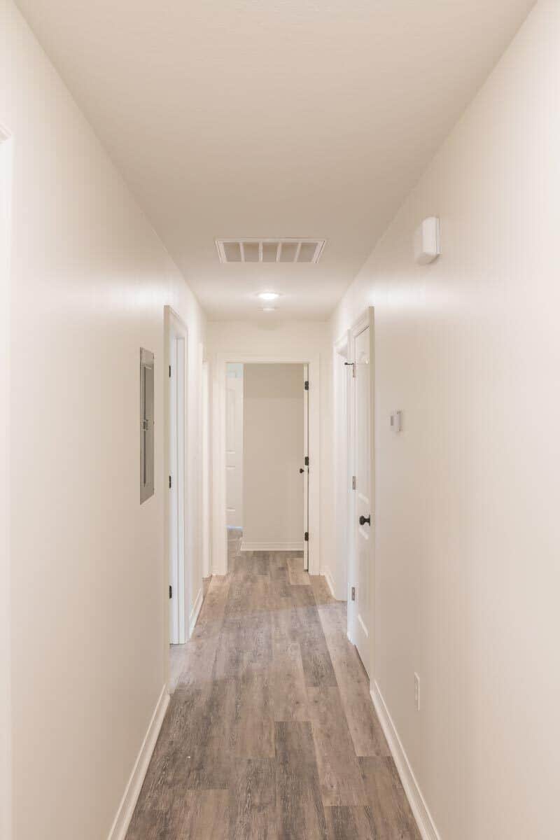 一条带有米色墙壁和硬木地板的走廊通往卧室。